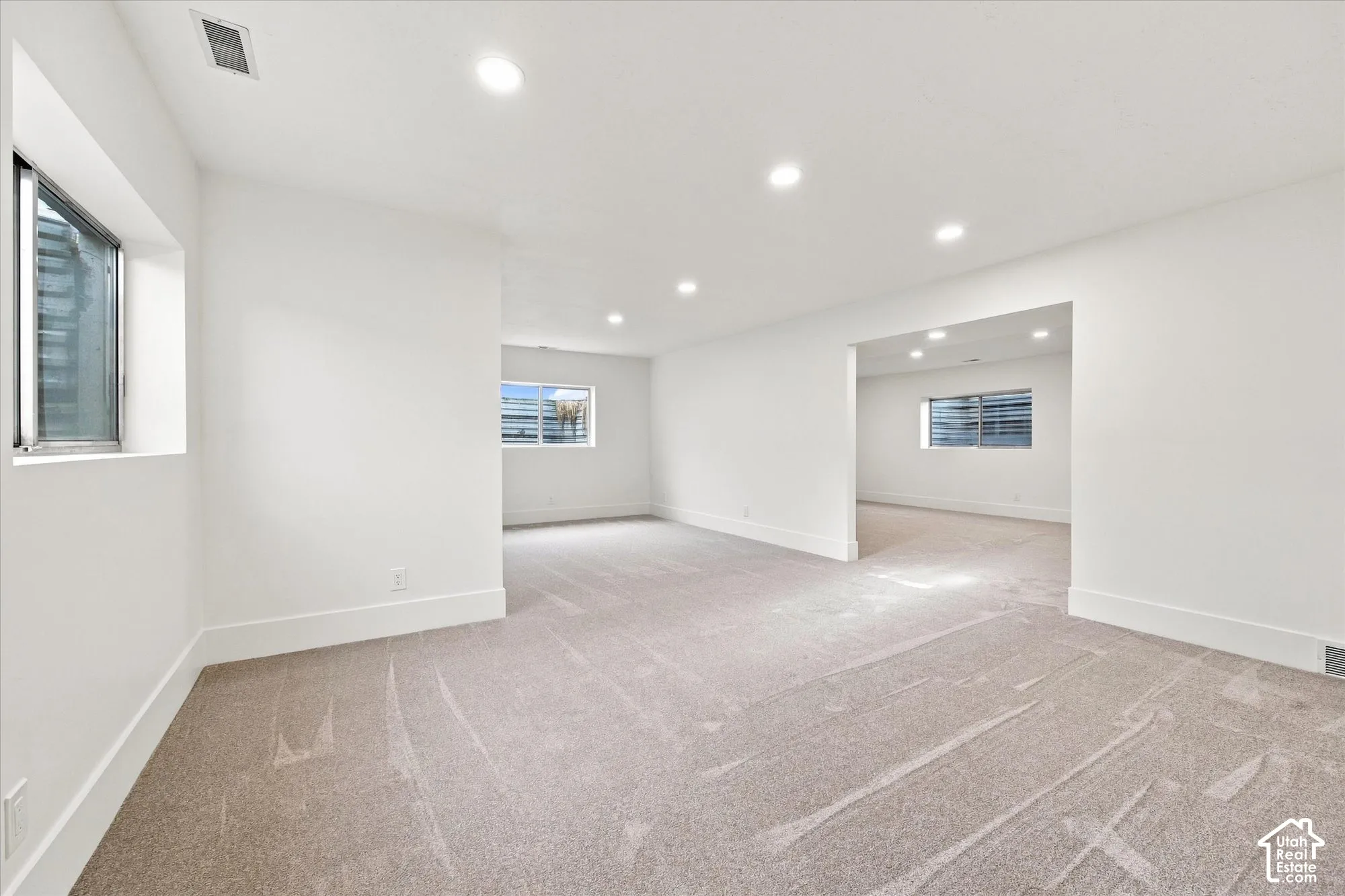Expansive open space with recessed lighting, light-toned carpet, and multiple windows