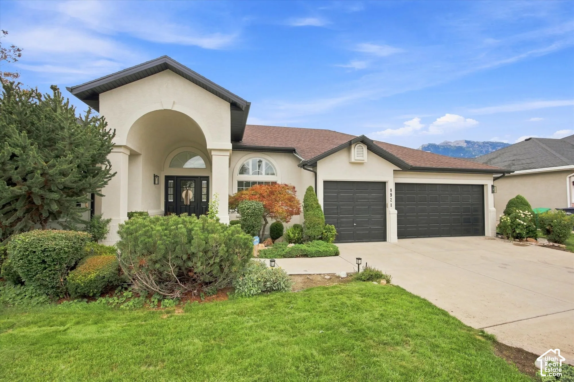 Stucco exterior with a covered entry, arched windows, and a two-car garage