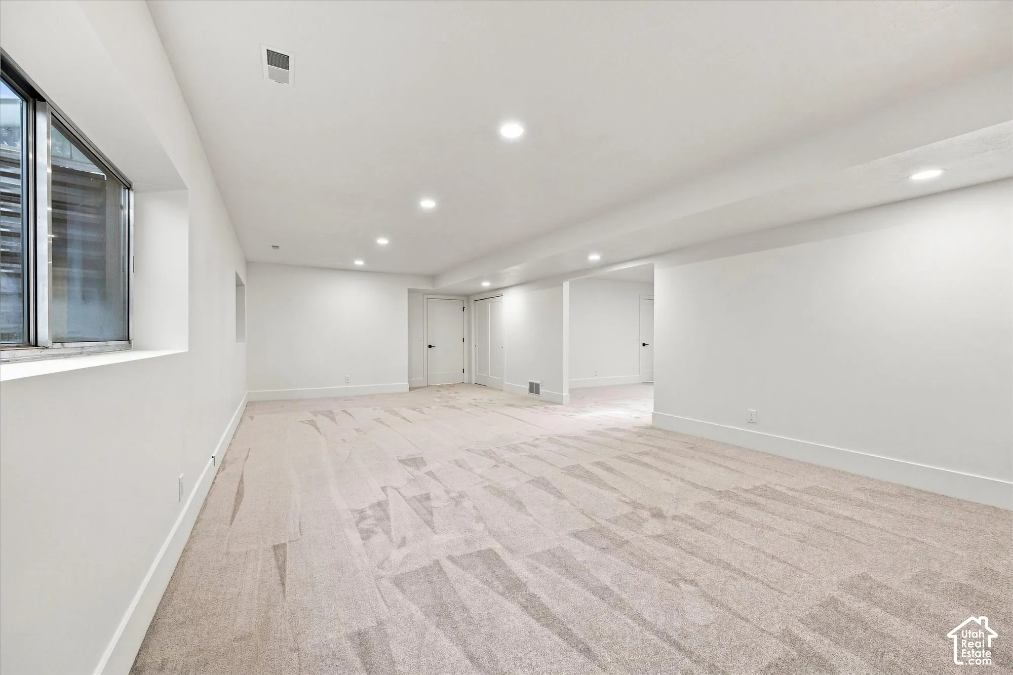 Recessed lighting, light-colored carpeting, white interior walls, white trim, and multiple white doors