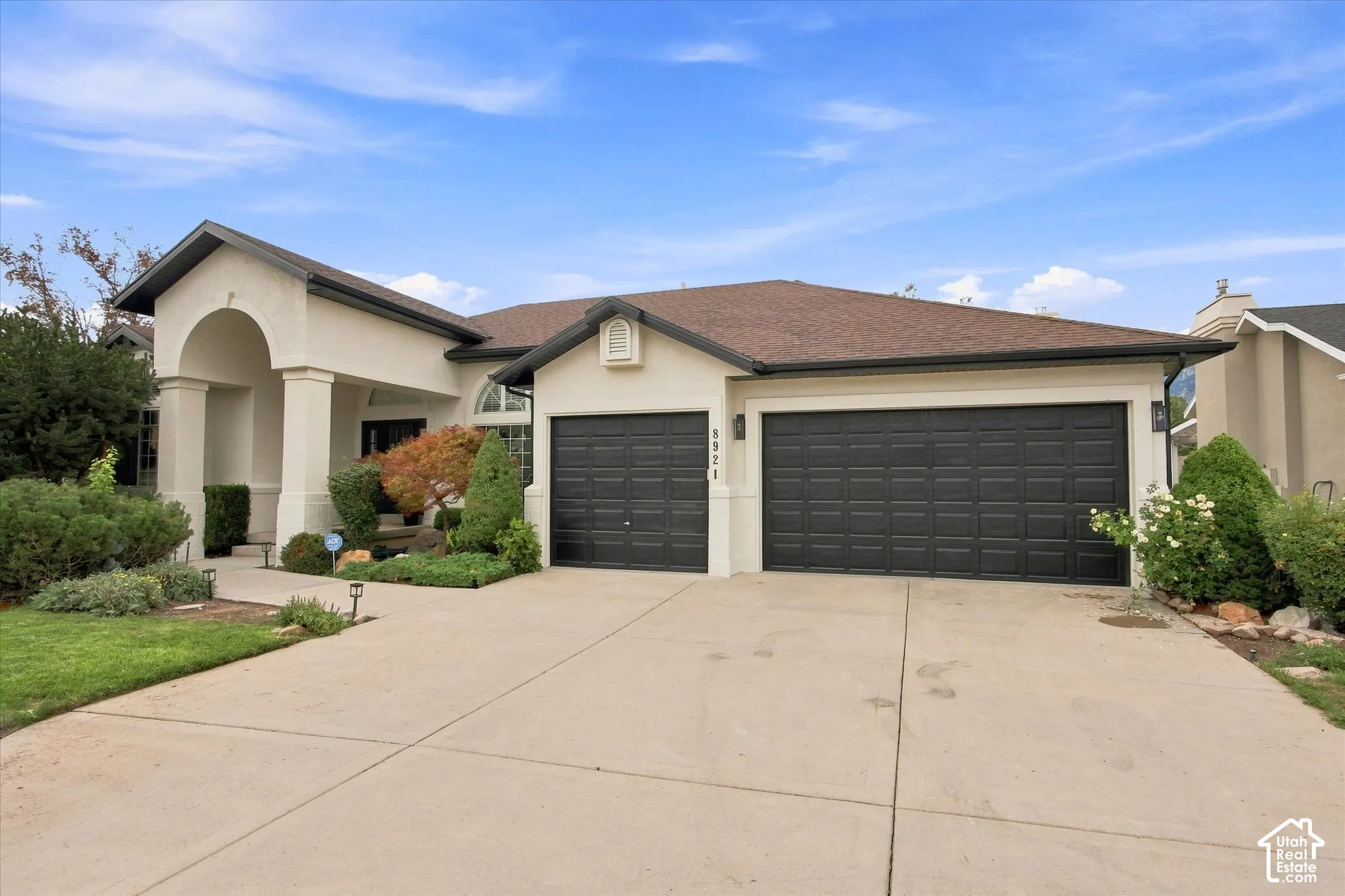 Stucco exterior with a covered entry, arched portico, column accents, and a two-car garage