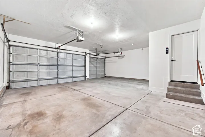 Two automatic garage doors, exposed ceiling joists, concrete flooring, interior access door, and three concrete steps