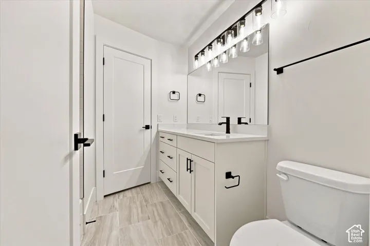 Modern bathroom featuring a white vanity with integrated sink, matte black hardware, a large mirror, and tiled flooring