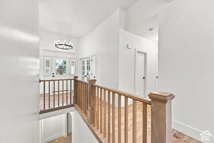 Hardwood flooring throughout, natural wood railing, white paneled doors, and an arched transom window
