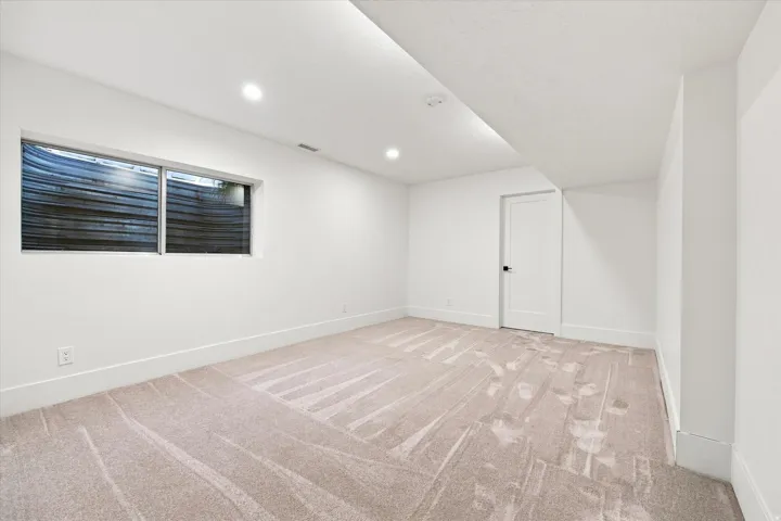 Recessed lighting illuminating a spacious room with light-toned carpet