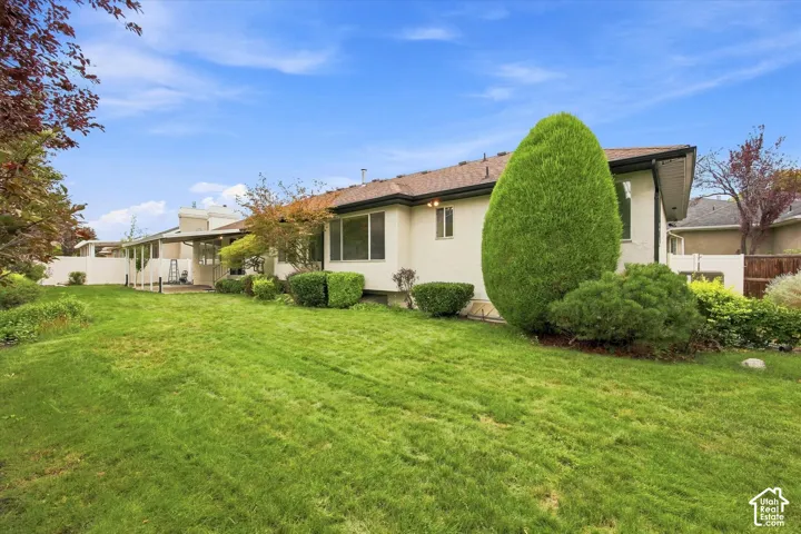 Expansive green lawn with mature landscaping and a covered patio area