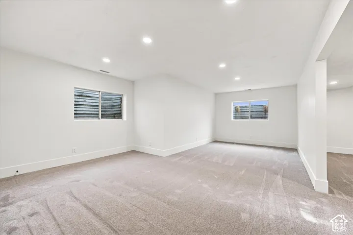 Recessed lighting illuminates the carpeted floor and white walls