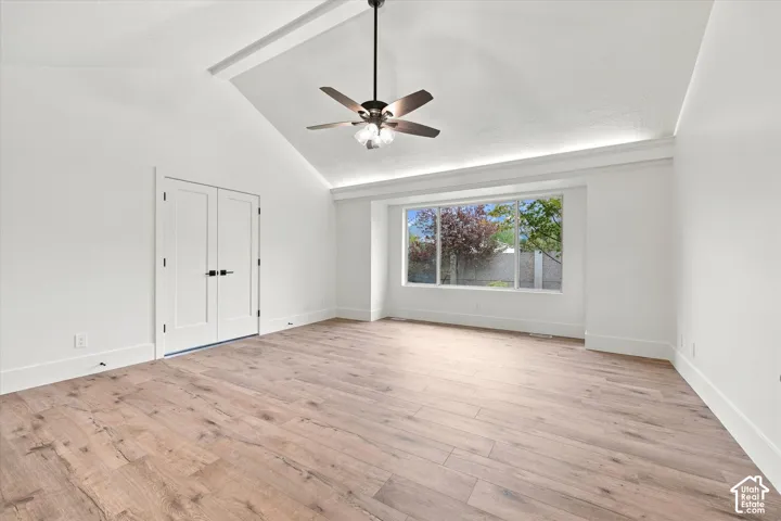 Vaulted ceiling with a ceiling fan, recessed lighting, wood-finish flooring, and white double doors