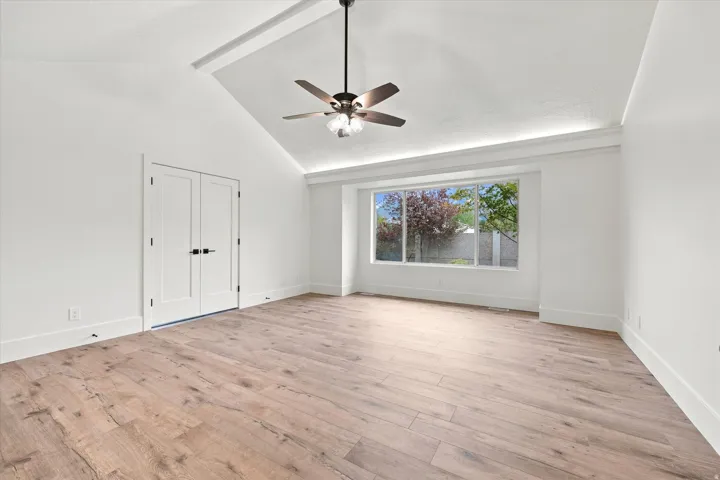 Vaulted ceiling with a ceiling fan, recessed lighting, wood-finish flooring, and white double doors