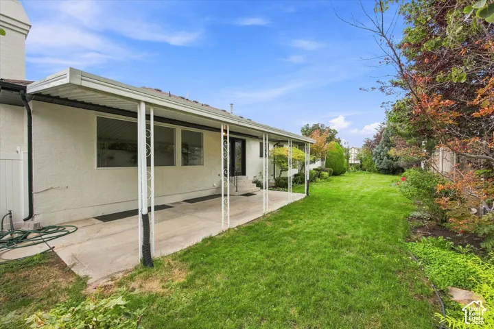 Expansive backyard featuring a concrete patio, covered patio structure, and a large grassy area