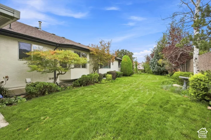Expansive lawn area with mature landscaping, architectural wall extensions, and a stone bird bath