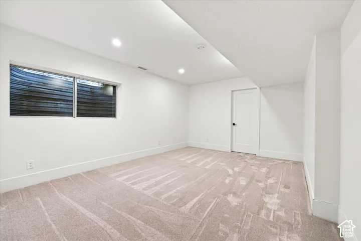 Recessed lighting illuminating a spacious room with light-toned carpet
