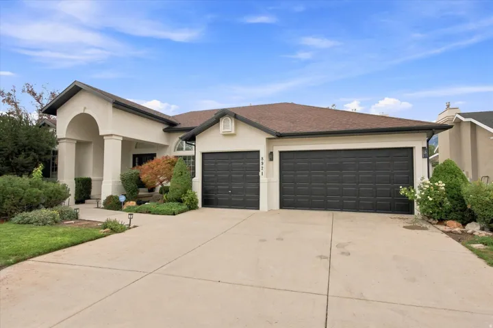 Stucco exterior with a covered entry, arched portico, column accents, and a two-car garage