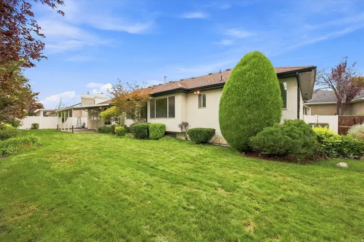 Expansive green lawn with mature landscaping and a covered patio area