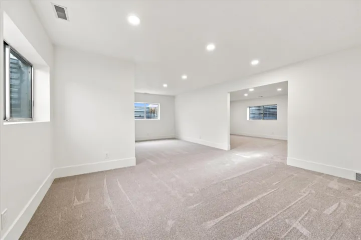 Expansive open space with recessed lighting, light-toned carpet, and multiple windows