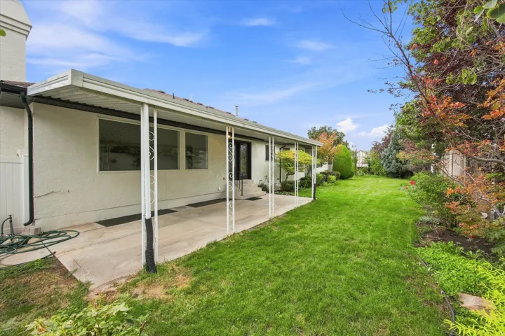 Expansive backyard featuring a concrete patio, covered patio structure, and a large grassy area