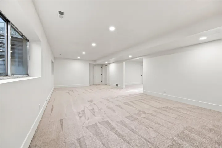 Recessed lighting, light-colored carpeting, white interior walls, white trim, and multiple white doors