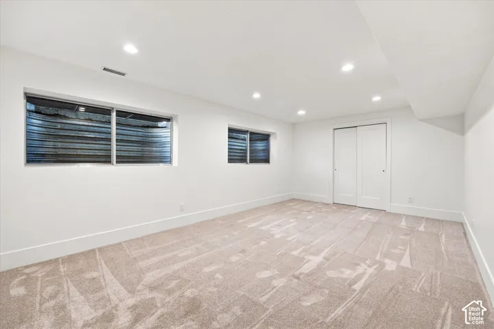 Recessed lighting illuminates the neutral-toned carpet and white walls