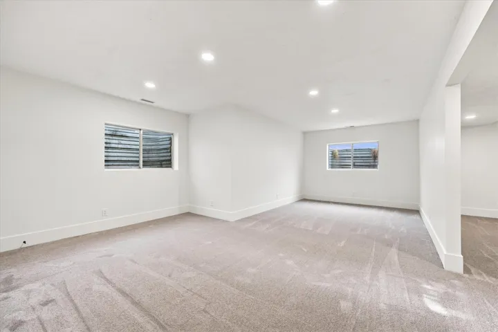 Recessed lighting illuminates the carpeted floor and white walls