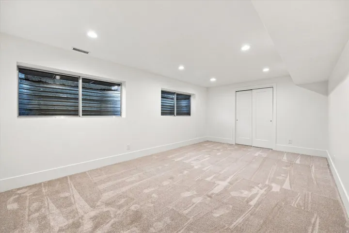 Recessed lighting illuminates the neutral-toned carpet and white walls