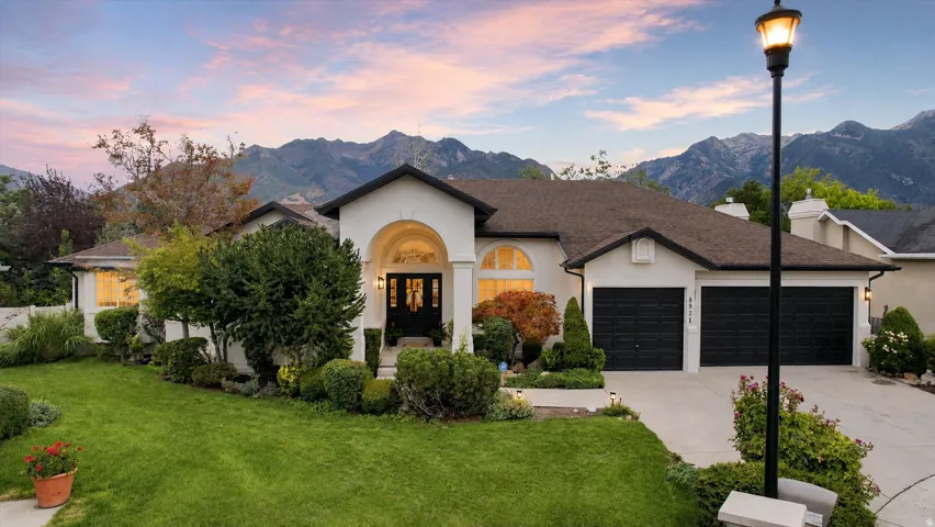 Stucco exterior with a dark shingle roof and black trim accents