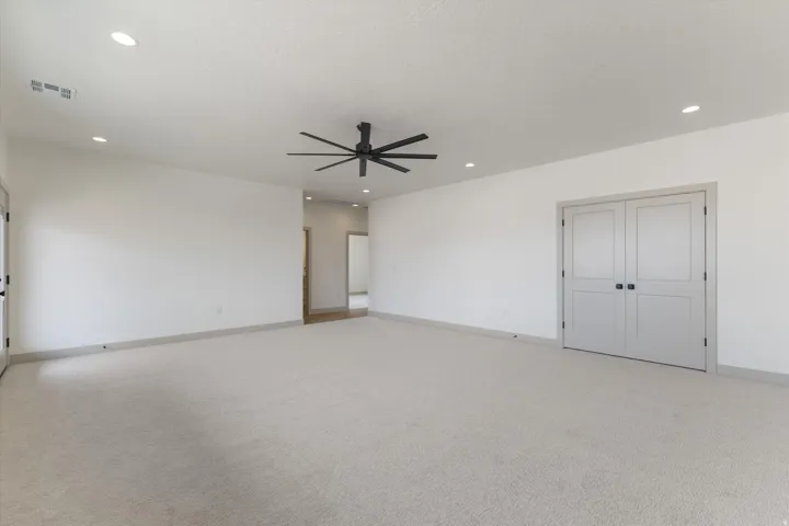 Recessed lighting, ceiling fan, neutral carpeting, and two-panel interior doors with black hardware