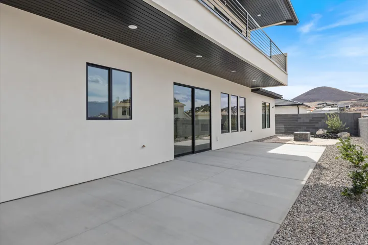 Expansive concrete patio with a modern stucco exterior and black-framed windows
