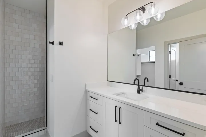 White vanity with recessed panel cabinetry and matte black hardware