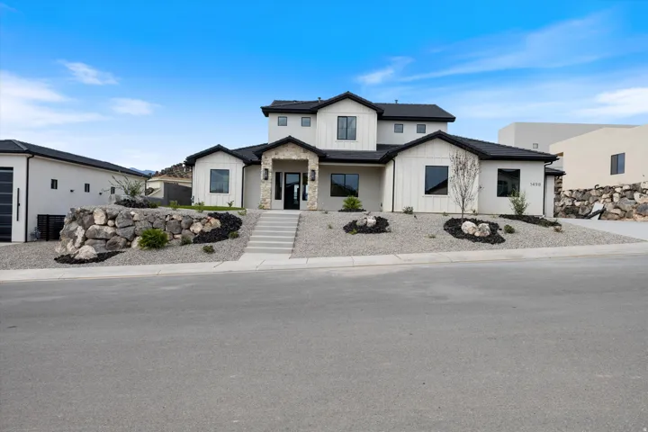 Modern exterior featuring white vertical siding, stone accents, black-framed windows, and a multi-level design