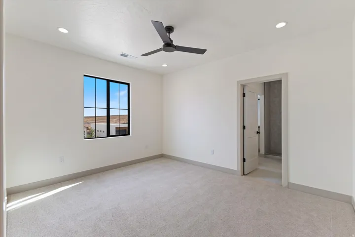 Recessed lighting, ceiling fan, black-trimmed window, light-toned carpeting, and a panel door with black hardware