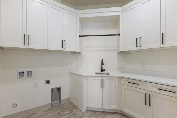 White shaker-style cabinetry, matte black hardware, integrated sink, stone-finish countertops, and wood-finish flooring