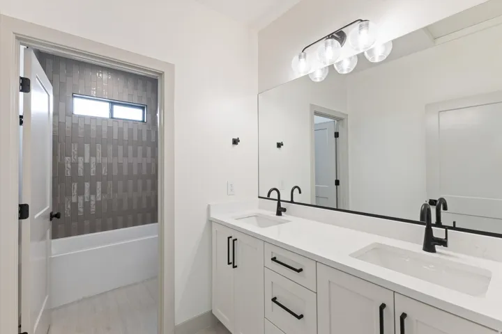 Double vanity with undermount sinks, wall-mounted mirror, and modern light fixture