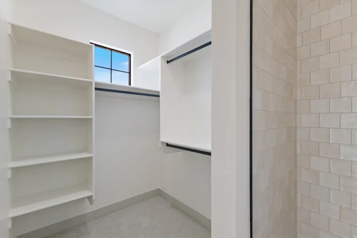 Walk-in closet with built-in shelving, hanging rods, and a window for natural light