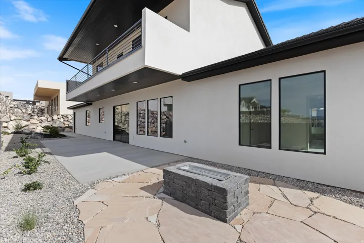 Exterior patio with a built-in stone fire feature, large format paver stones, and a concrete patio section