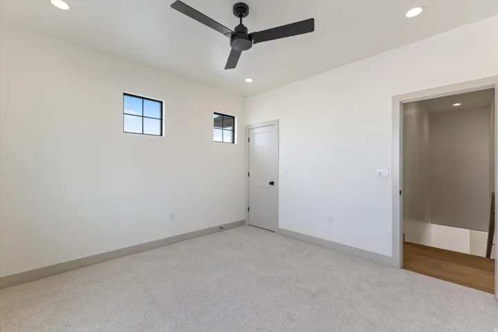 Recessed lighting, light-toned carpeting, a ceiling fan, and modern square windows