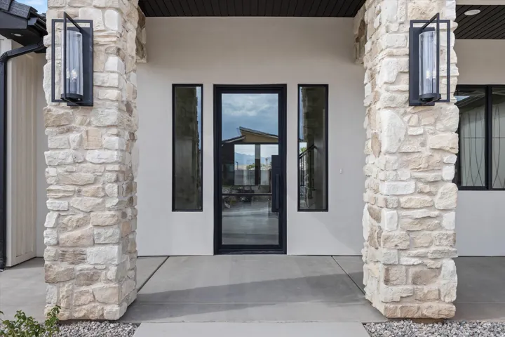 Stone veneer columns frame the entry, featuring a full-light entry door and two sidelight windows