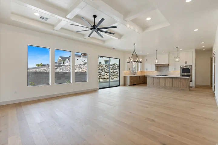 Open-concept living space featuring wood-finish flooring, a coffered ceiling with a ceiling fan, and recessed lighting