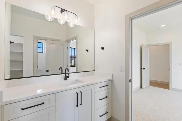 Vanity featuring white cabinetry with matte black hardware, integrated sink, and white countertop