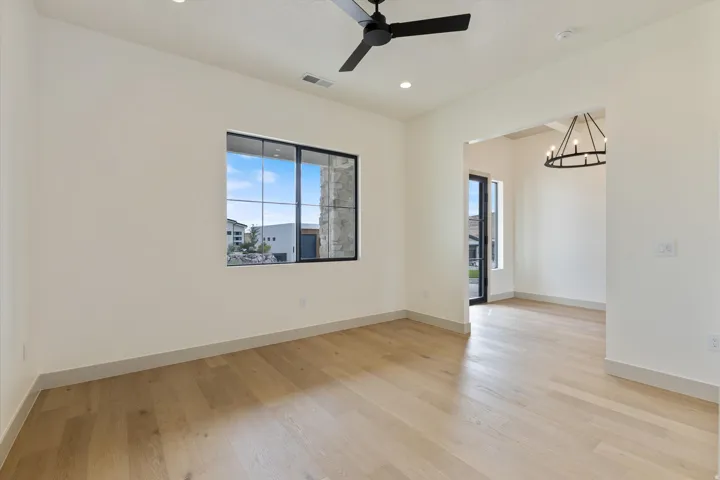 Light wood-finish flooring, recessed lighting, and a black ceiling fan complement the neutral wall tones