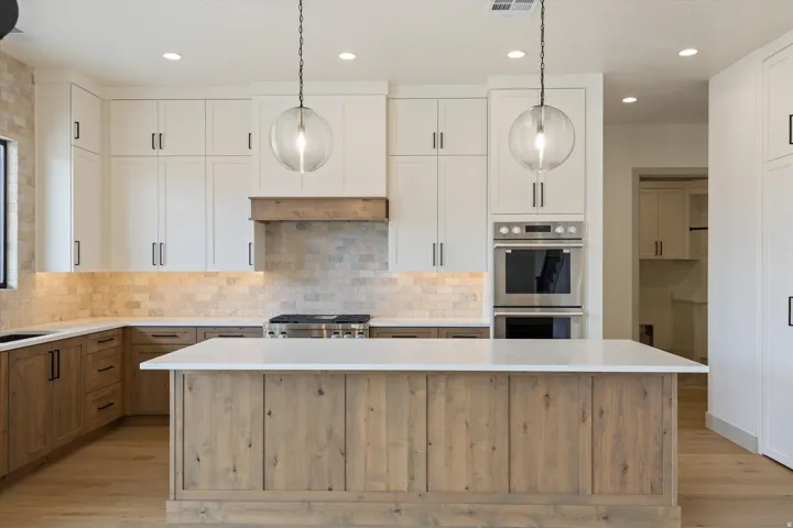 Gourmet kitchen with two-tone cabinetry, a large center island, integrated stainless steel appliances, and a tiled backsplash