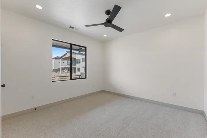 Recessed lighting, wall-to-wall carpeting, modern ceiling fan, and large window with dark trim