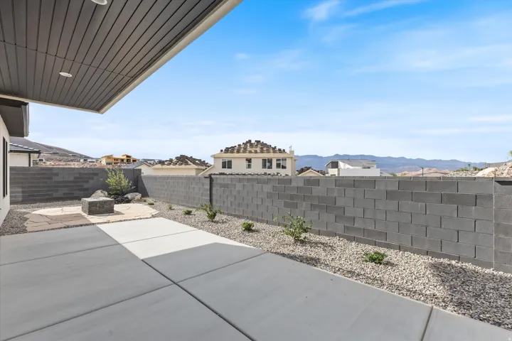 Covered patio with integrated lighting, concrete paver patio, xeriscape landscaping, full block wall perimeter, and a central stone patio area