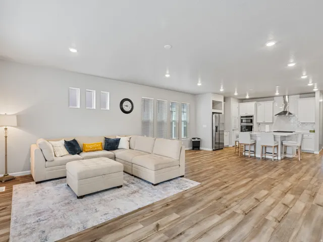 Open-concept living space with wood-finish flooring, recessed lighting, and multiple windows