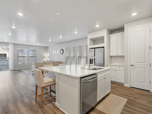 Open-concept living space featuring wood-finish flooring, recessed lighting, and a kitchen island with an integrated sink