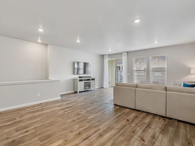 Spacious living area featuring wood-finish flooring, recessed lighting, and a sliding glass door for outdoor access