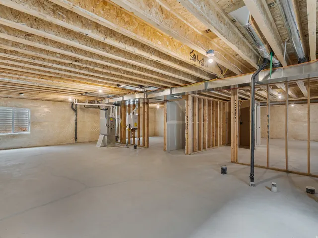 Unfinished lower level with concrete flooring, exposed ceiling joists, and framed interior walls