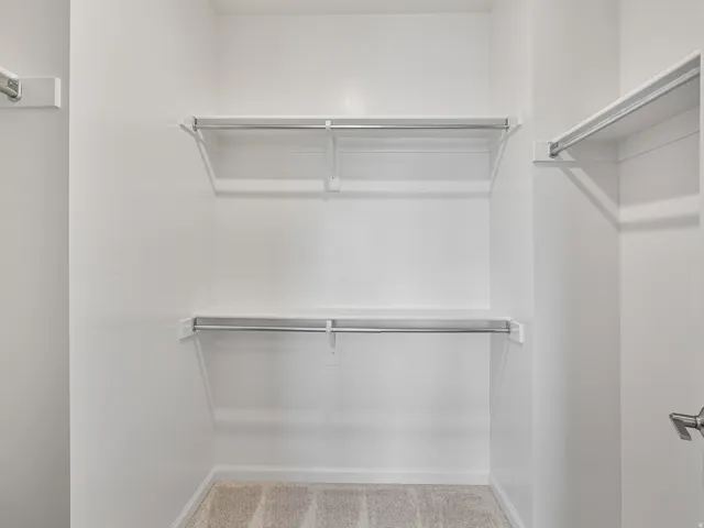 Walk-in closet featuring white wire shelving and hanging rods