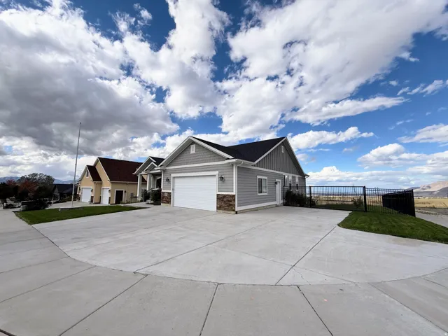 Contemporary siding exterior with stone accents, a two-car garage, concrete driveway, and black metal fencing