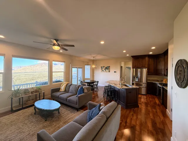 Expansive windows, recessed ceiling lighting, wood-finish flooring, dark wood cabinetry, and a kitchen island with seating