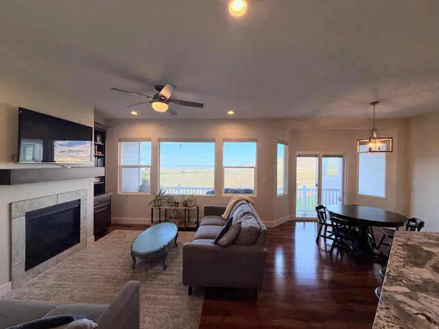 Integrated living area with a stone-surround fireplace, built-in shelving, a ceiling fan with integrated lighting, and recessed ceiling lights