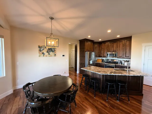 Wood-finish flooring, recessed lighting, and a kitchen island with granite countertops